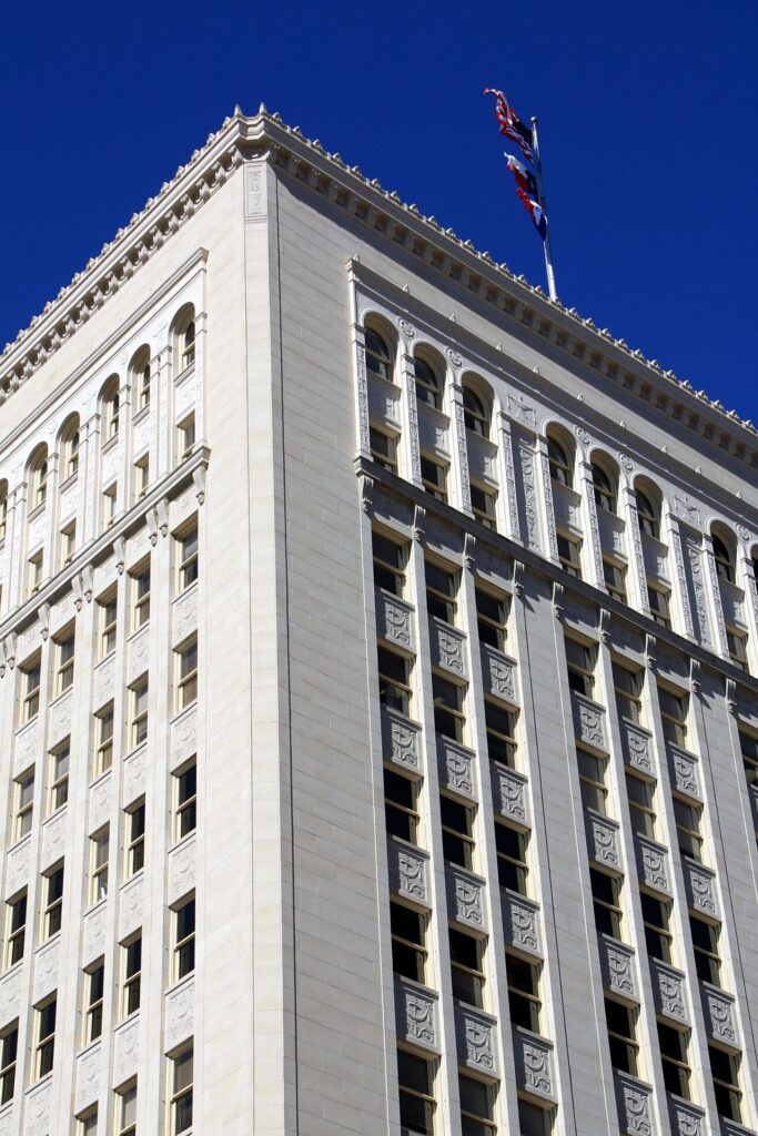 The top corner of the Municipal Plaza Building in downtown San Antonio, where City Council meets, with flags flying.